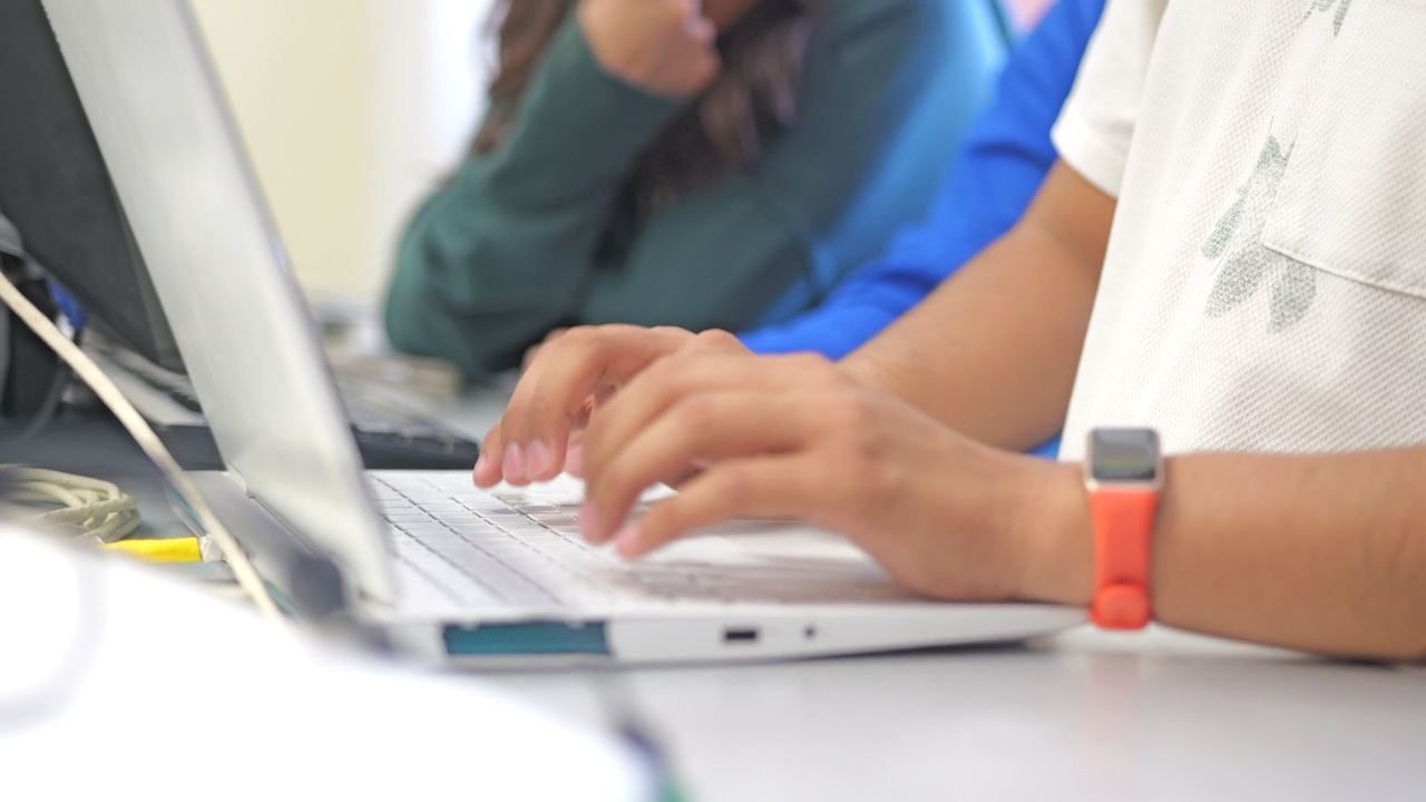 Students typing on laptops in a classroom